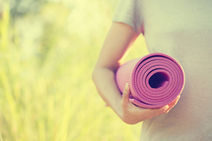 Kvinna med ihoprullad yogamatta.
